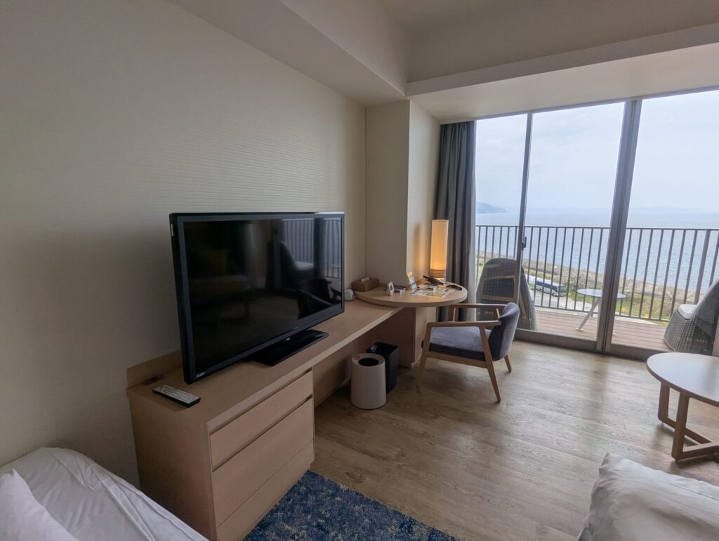 AQUA SQUAREオーシャンビュールームのデスクとテレビと窓から海が見える様子