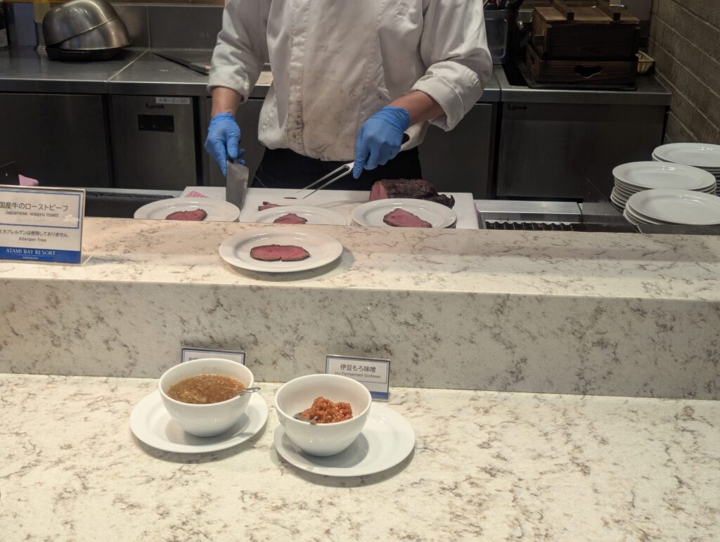 シェフが国産牛ローストビーフをその場で切り分けるライブキッチン、手前に伊豆もろ味噌のソース