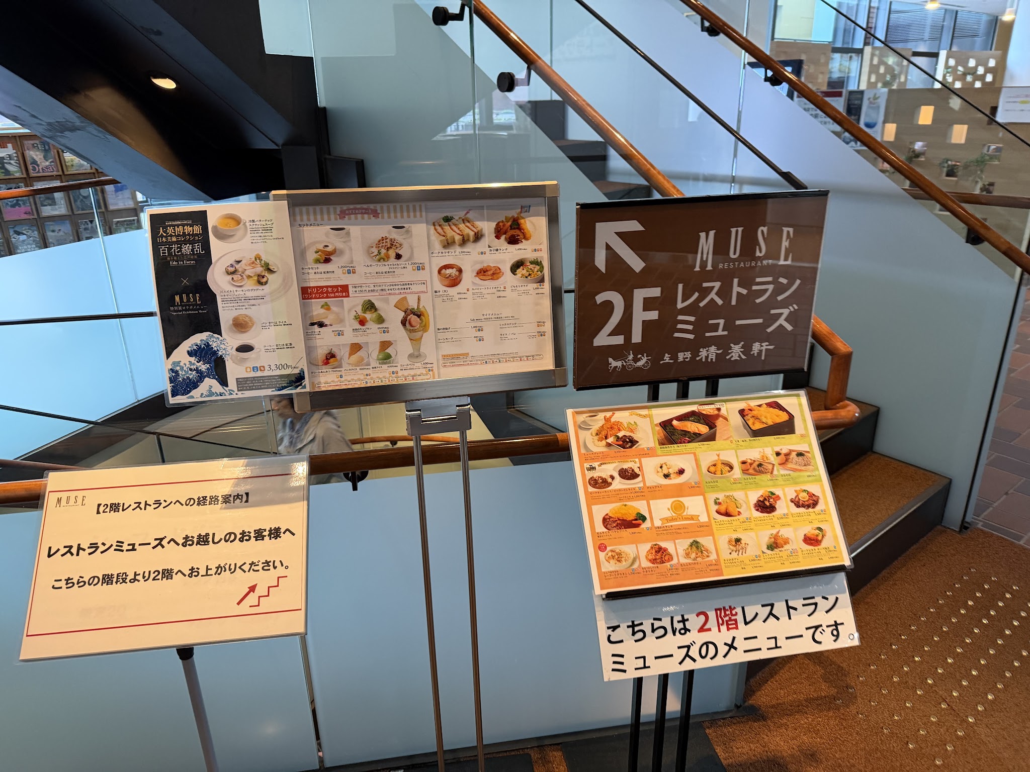 レストランミューズのある2階を示す館内案内と階段
