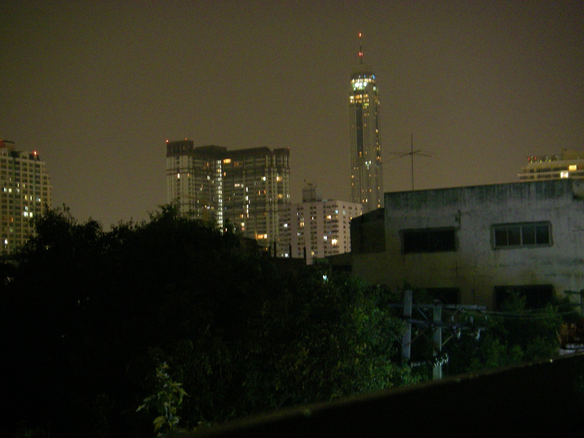 夜の窓の外に並ぶ高層ビルと、ひときわ高い塔
