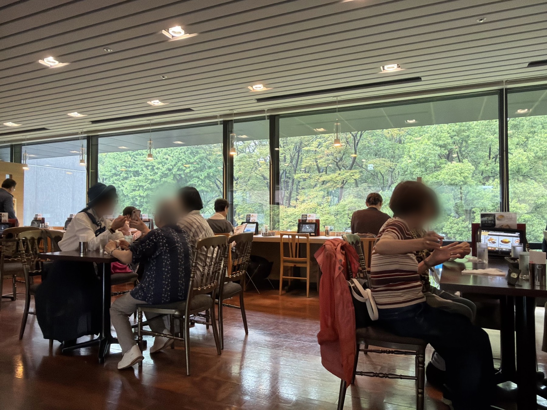 大きな窓、テーブル席、窓向きのカウンター席がある店内