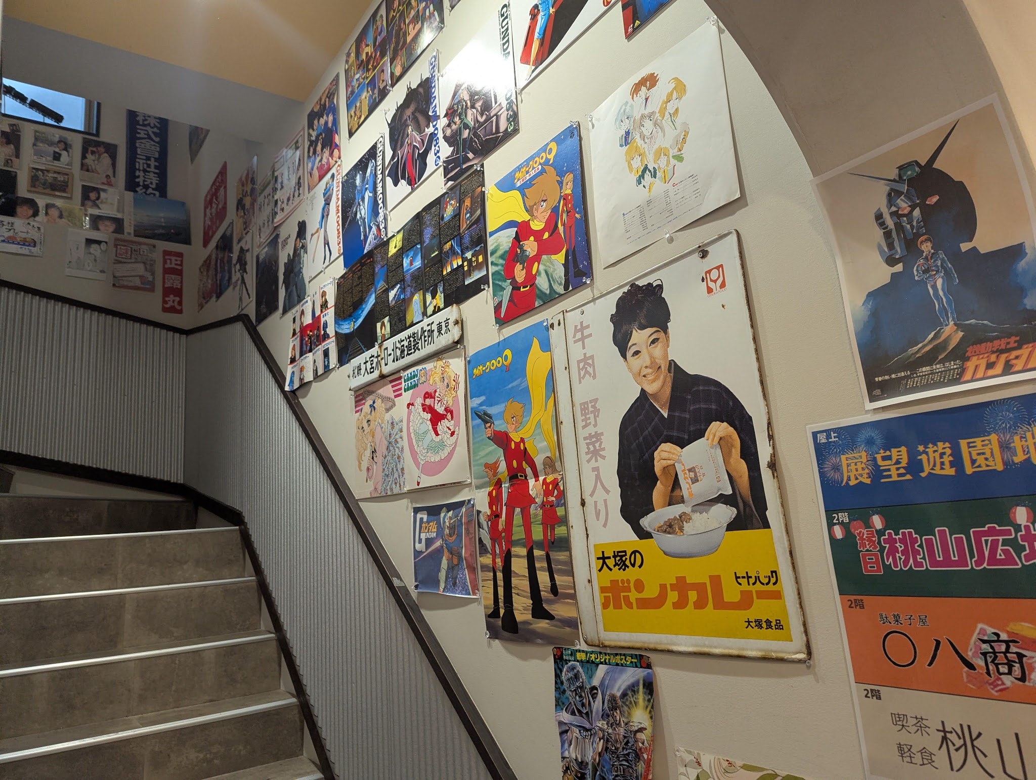階段脇の壁を埋める看板とポスター