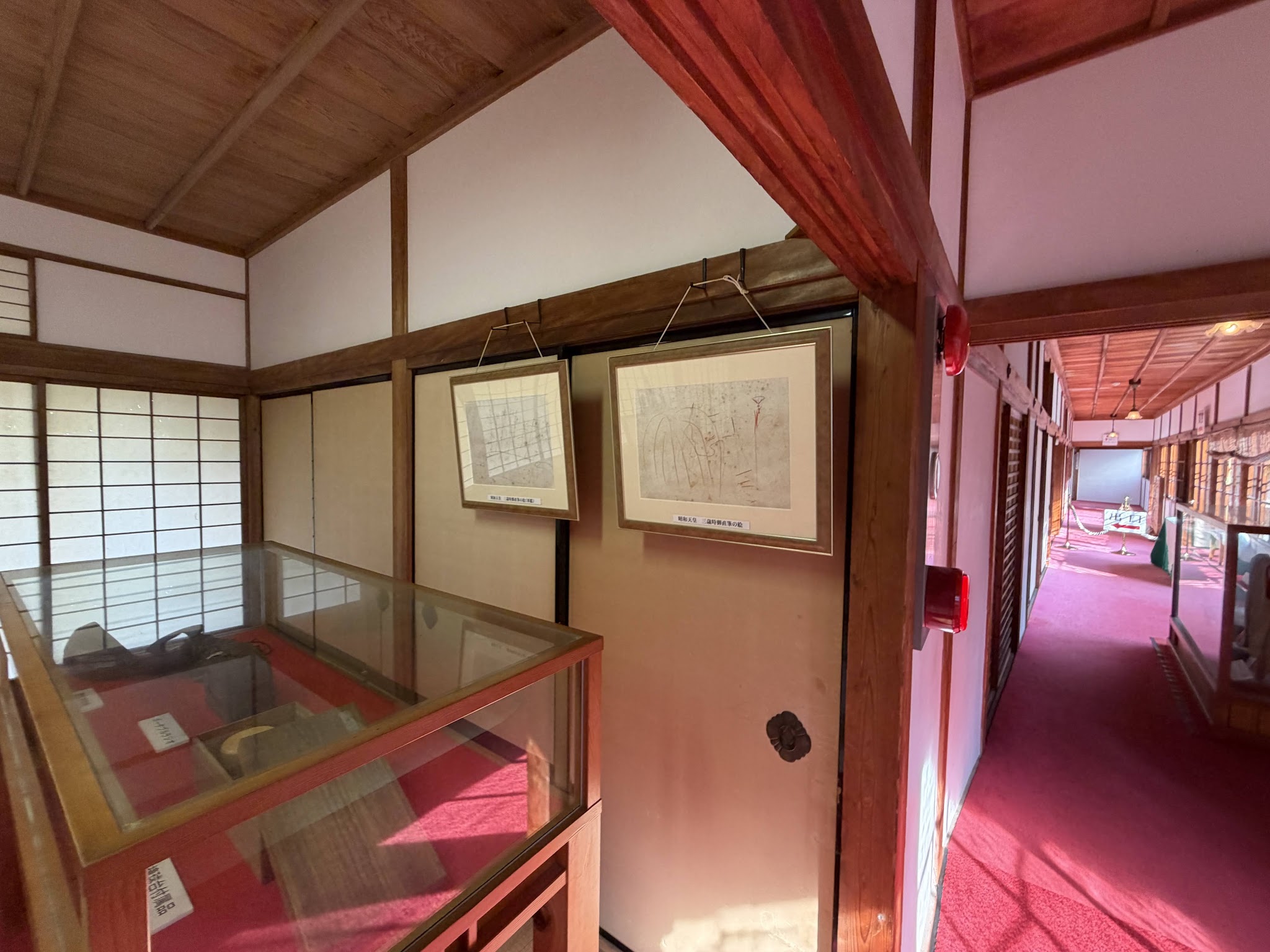赤い敷物と展示ケースが続く西附属邸の廊下